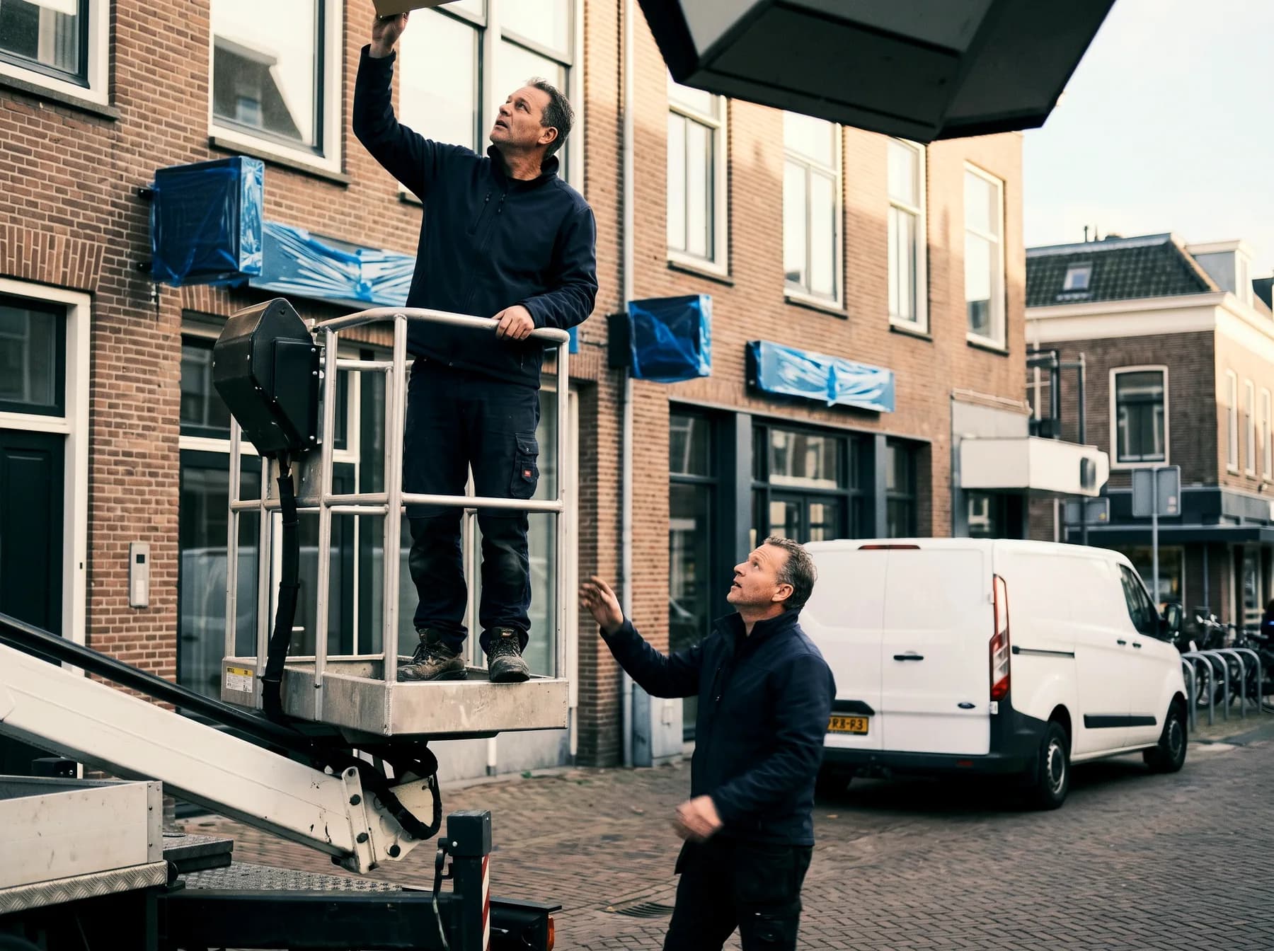 Monteur op de hoogwerker kijkt omhoog naar een opklarende lucht